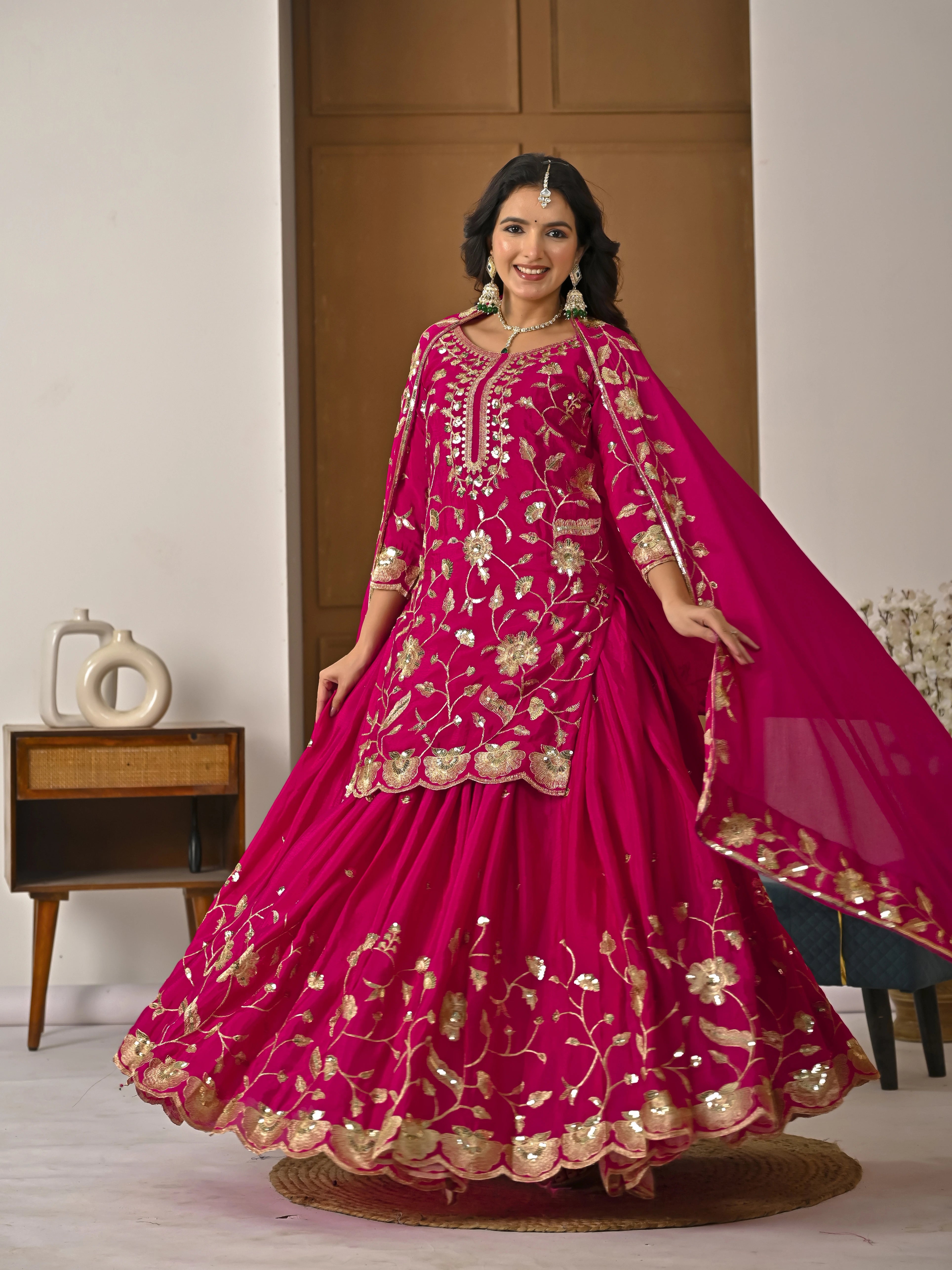 Woman in a pink traditional outfit with gold embroidery in a room setting